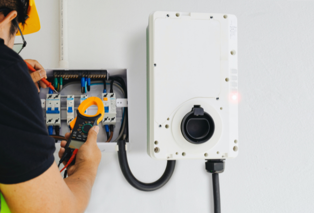 Electrician testing EV charger installation and electrical panel in Snohomish County home.