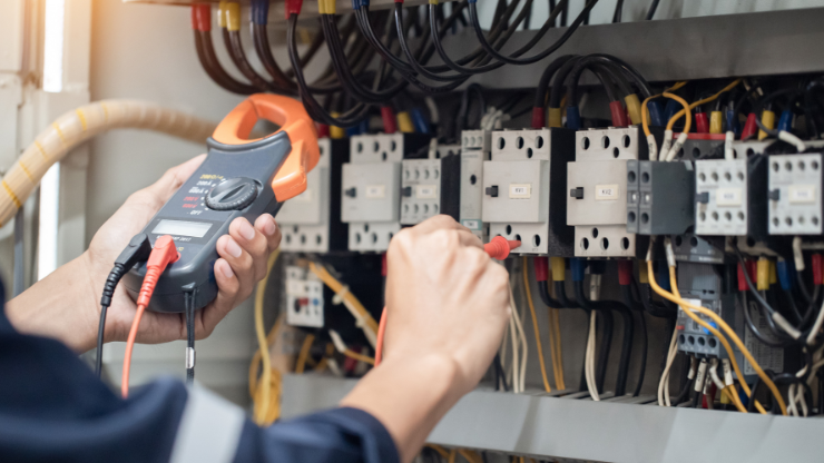 Electrician testing electrical panel with clamp meter, dedicated circuit inspection.