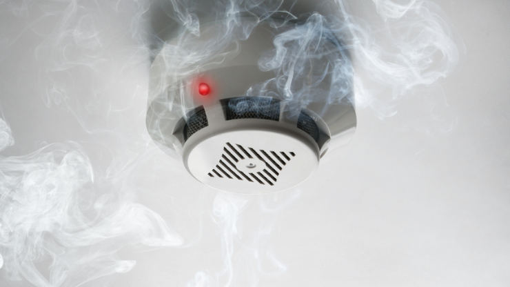 Smoke detector with illuminated red light, illustrating electrical safety and fire prevention.
