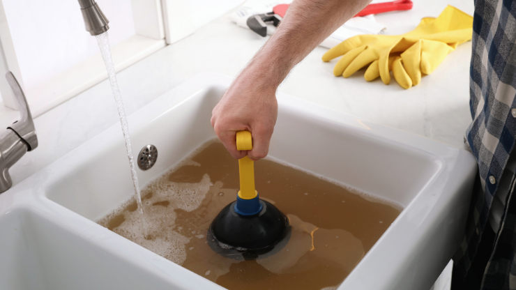 Backed up clogged drain that is being plunged by a homeowner