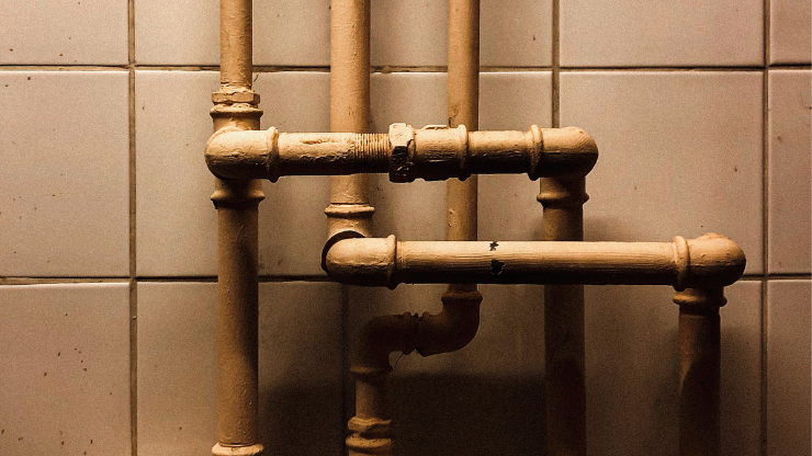 Older galvanized steel plumbing pipes and fittings in a residential setting.
